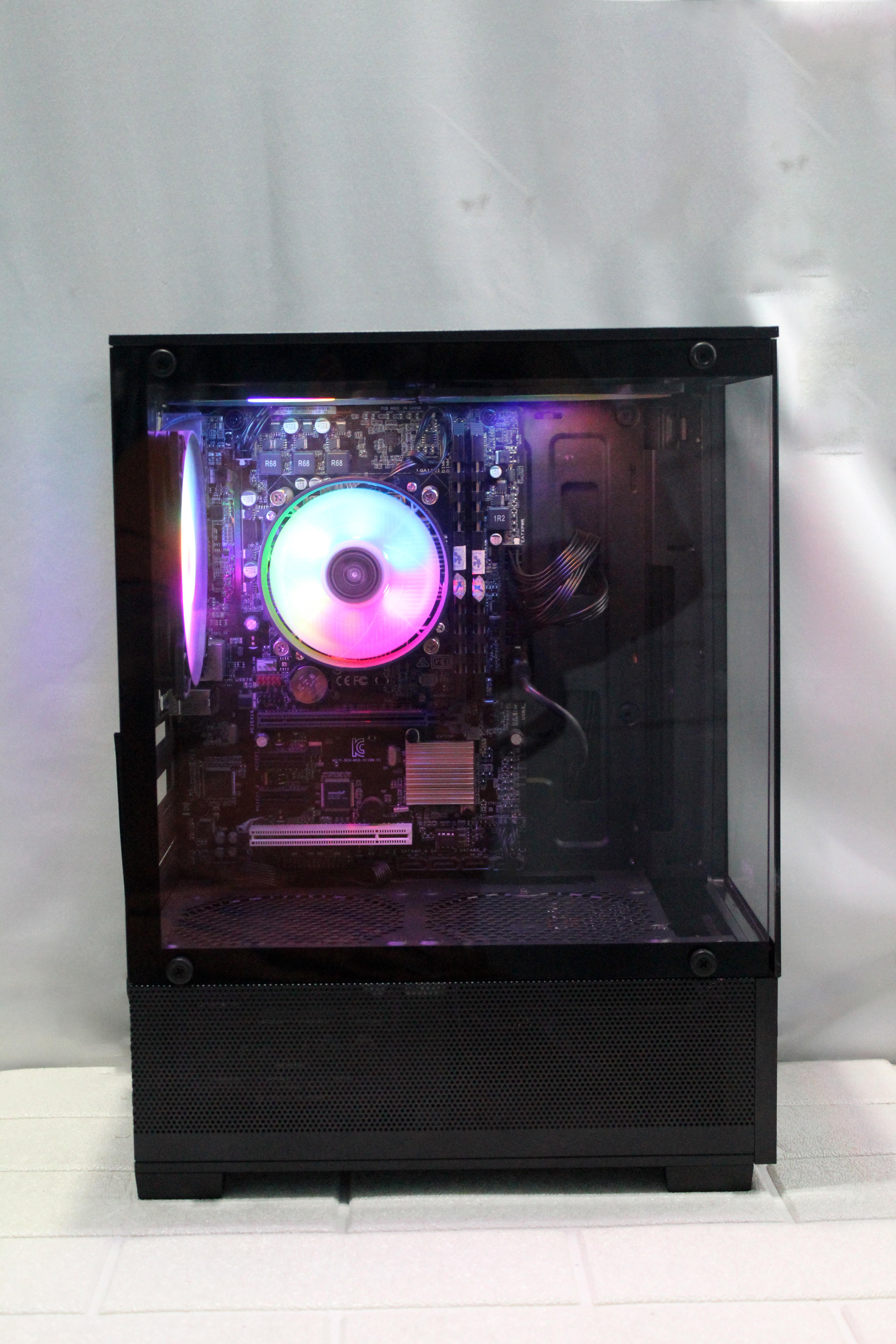 Modern gaming computer with vibrant LED fans and sleek glass design, showcasing high-performance components.